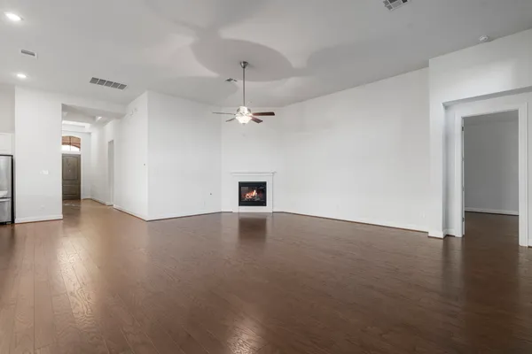 a view of an empty room with chandelier fan and fire place