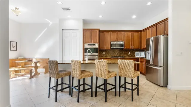 a kitchen with stainless steel appliances granite countertop a stove a sink a oven with a dining table and chairs