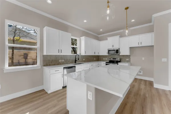 a kitchen with kitchen island a counter top space a sink stainless steel appliances and cabinets