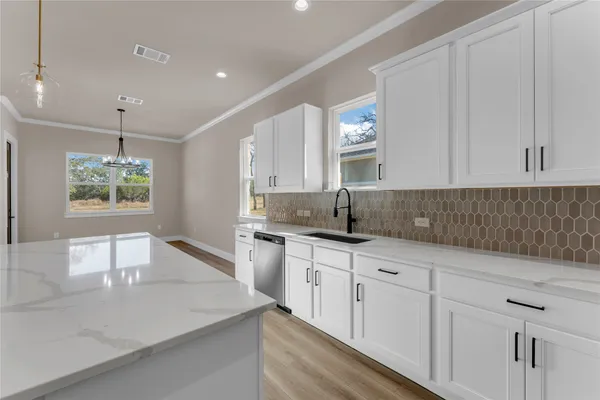 a kitchen with white cabinets appliances and a sink