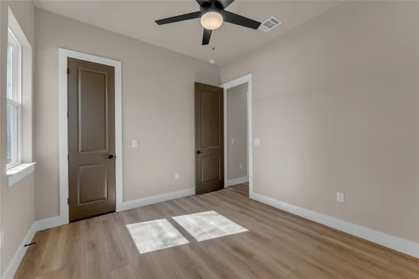 an empty room with wooden floor and windows