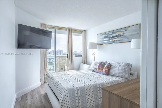 a bedroom with a large bed and a flat tv screen on dresser