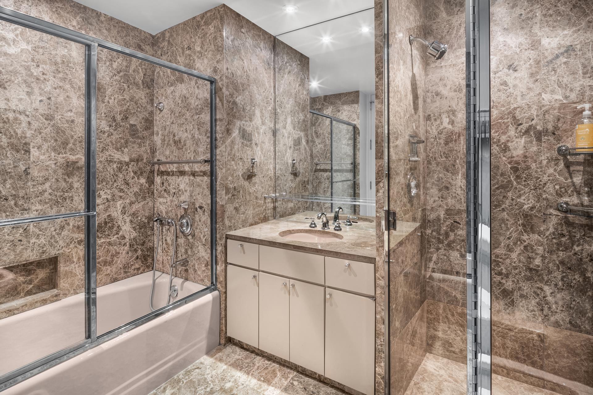 641 5th Avenue, Unit 42H Manhattan, NY 10022 - Photo 11 of 16 a bathroom with a bathtub sink vanity and mirror