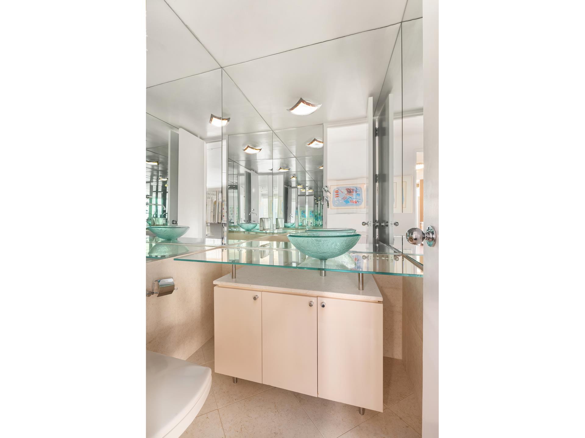 641 5th Avenue, Unit 42H Manhattan, NY 10022 - Photo 12 of 16 a bathroom with a double vanity sink and mirror