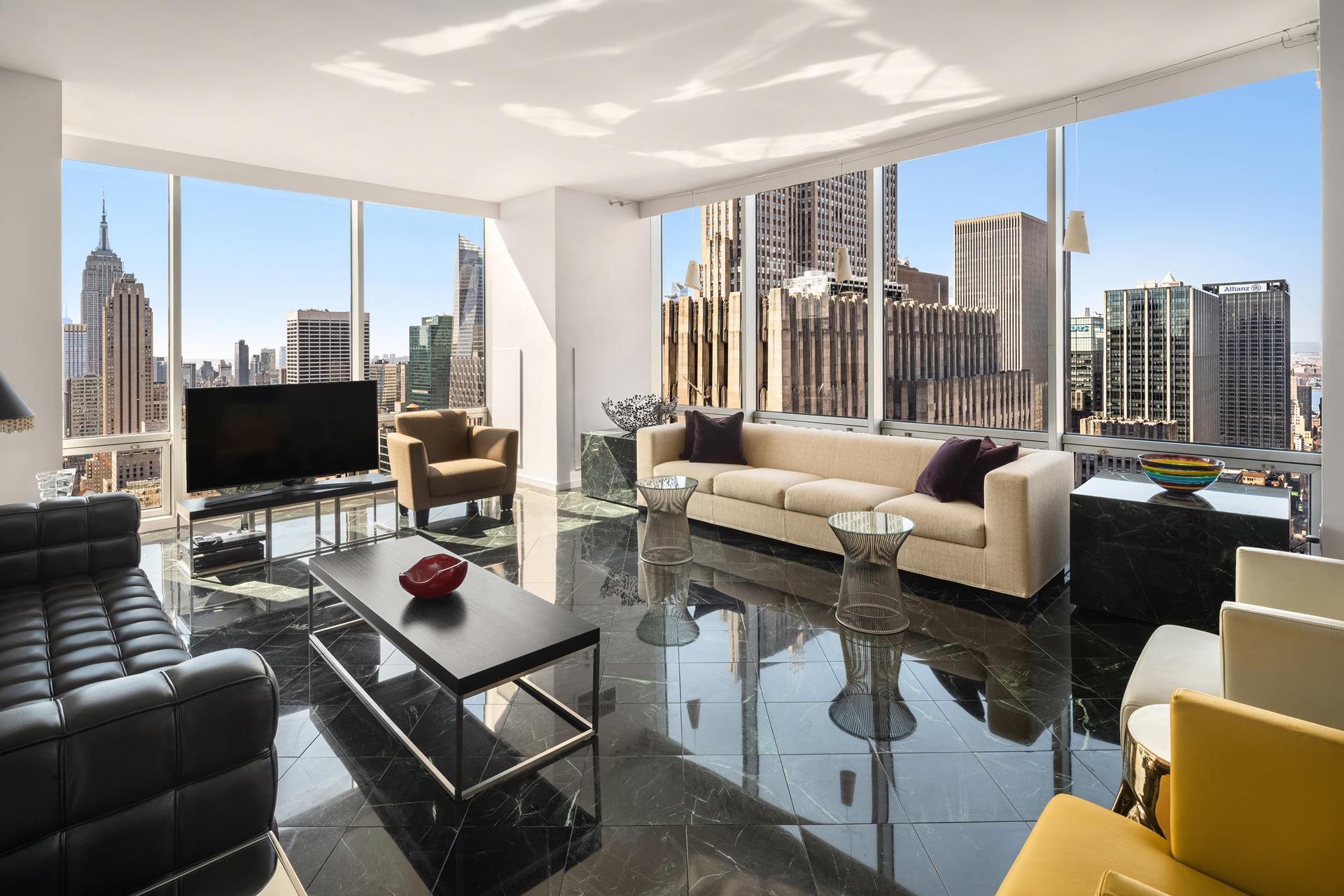 641 5th Avenue, Unit 42H Manhattan, NY 10022 - Photo 3 of 16 a living room with furniture a flat screen tv and a floor to ceiling window