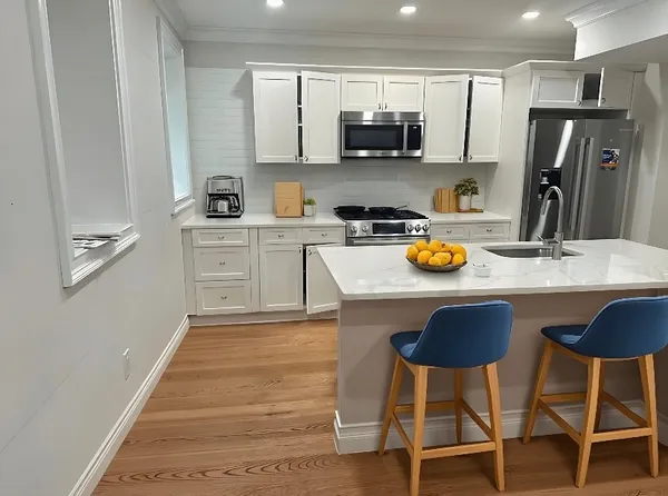 a kitchen with stainless steel appliances granite countertop a sink a stove a refrigerator cabinets and chairs