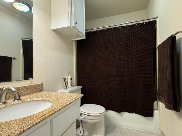 a bathroom with a granite countertop sink toilet and shower