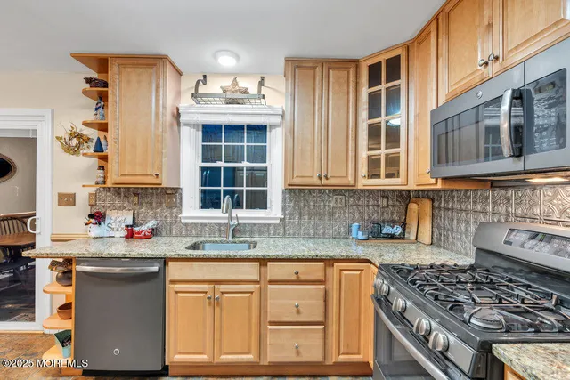 a kitchen with stainless steel appliances granite countertop a stove top oven a sink dishwasher and cabinets with wooden floor