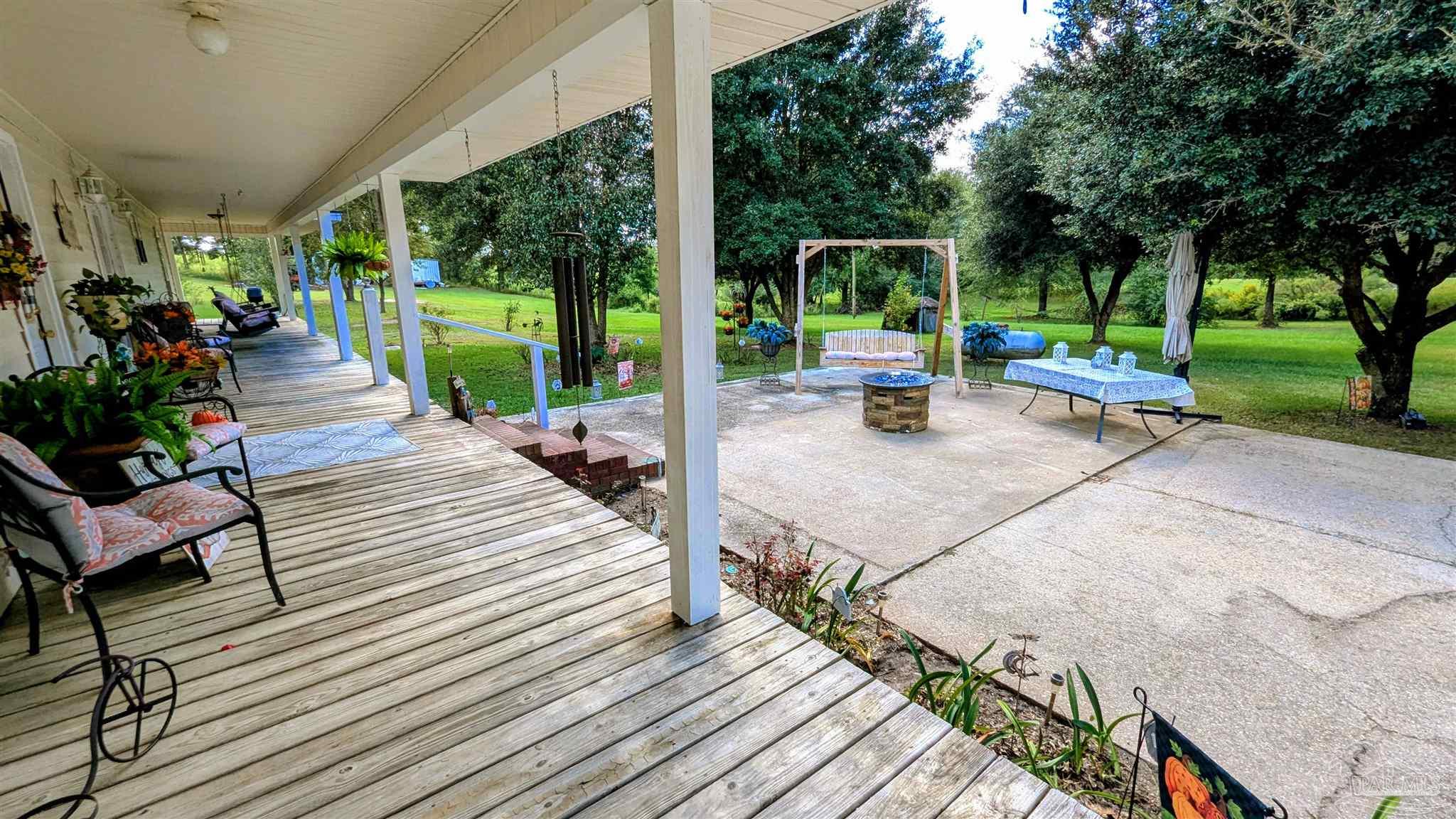 3171 Sam Sullivan Road Millry, AL 36558 - Photo 3 of 72 a view of a patio with table and chairs potted plants with wooden floor and fence