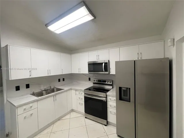 a kitchen with stainless steel appliances white cabinets and a refrigerator