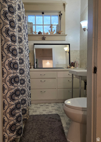 142 West 400 North Logan, UT 84321 - Photo 20 of 35 Bathroom featuring a window with decorative trim, vanity cabinetry with multiple drawers, a wall-mounted sink, and hexagonal floor tiling