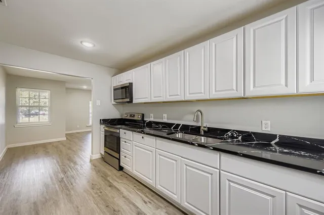 a kitchen with granite countertop a sink a stove and cabinets