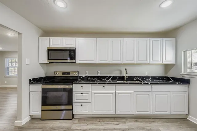 a kitchen with granite countertop white cabinets and stainless steel appliances