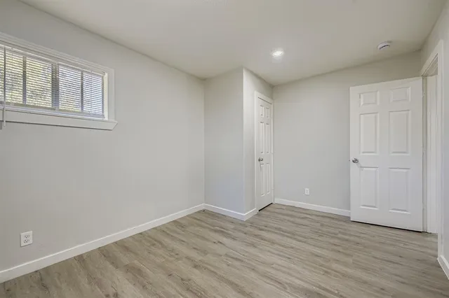 a view of an empty room with wooden floor and windows