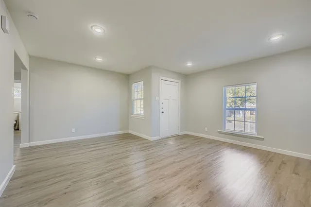 an empty room with wooden floor and windows
