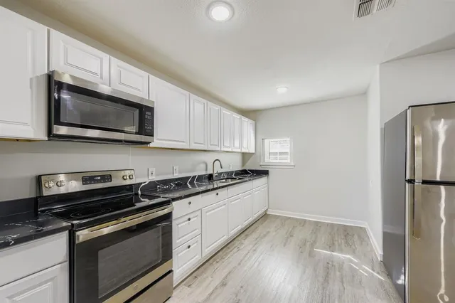 a kitchen with stainless steel appliances granite countertop a stove microwave and refrigerator