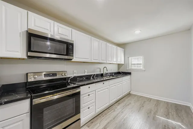 a kitchen with granite countertop a stove top oven a sink dishwasher and cabinets with wooden floor