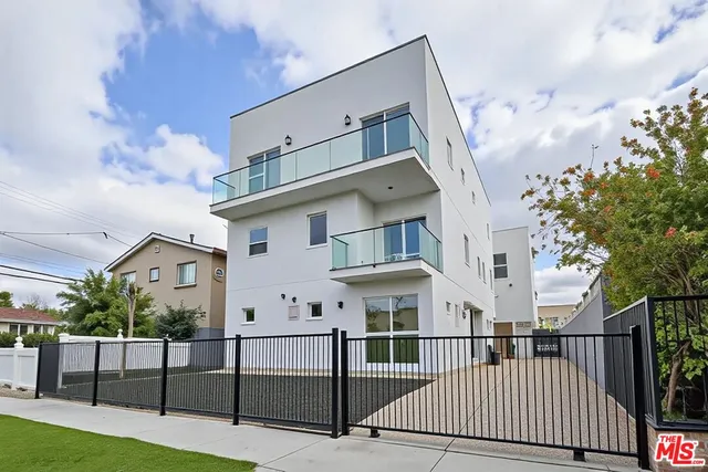 a view of a white house with iron fence