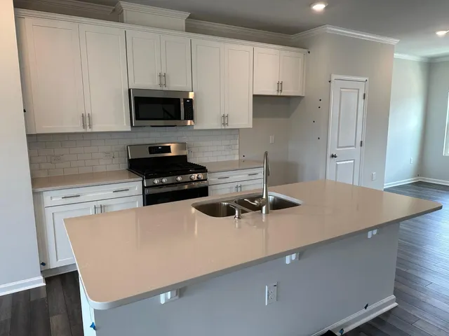 a kitchen with a sink a stove and white cabinets