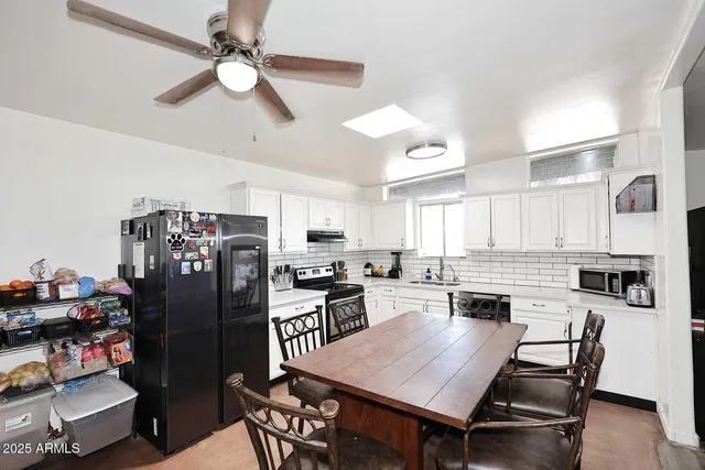 a kitchen with stainless steel appliances a stove a refrigerator a dining table and chairs with wooden floor