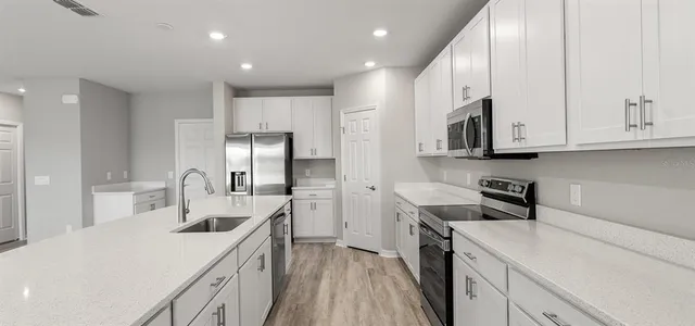 a kitchen with white cabinets a sink and appliances