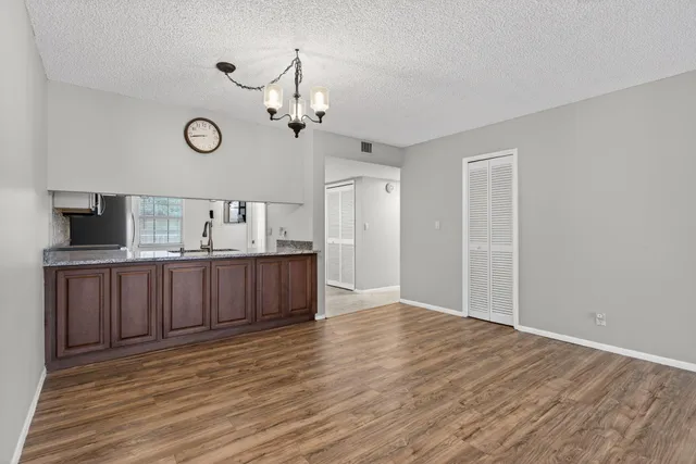 an empty room with windows and chandelier fan