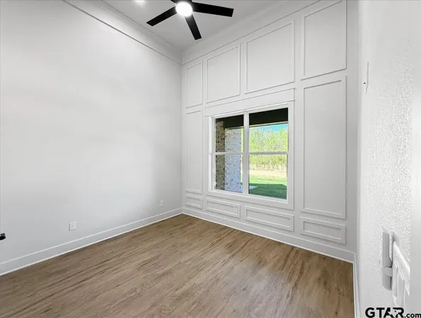 an empty room with wooden floor fan and windows