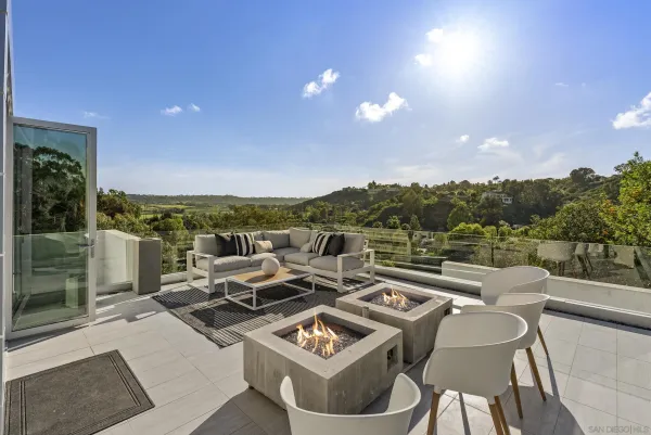 a view of a patio with couches and table and chairs with wooden floor and fence
