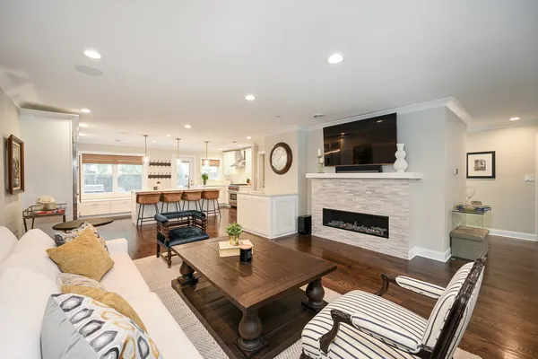 a living room with furniture a fireplace a flat screen tv and kitchen view