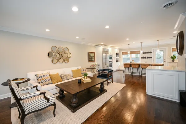 a living room with couches and kitchen view with wooden floor