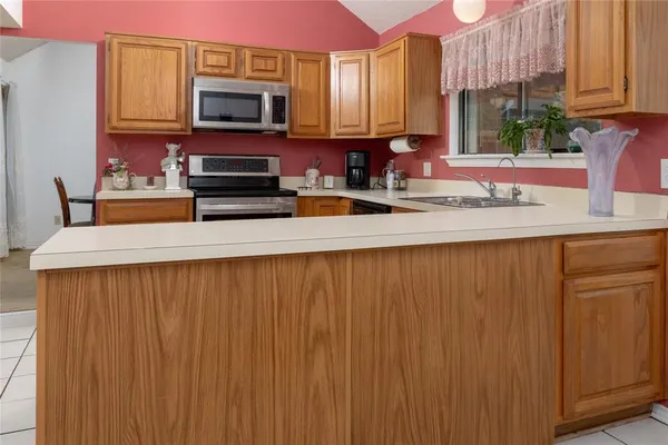 a kitchen with stainless steel appliances a sink a microwave a refrigerator and cabinets