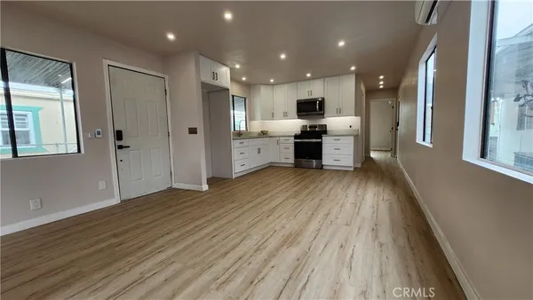 a large kitchen with a large counter top a sink stainless steel appliances and cabinets
