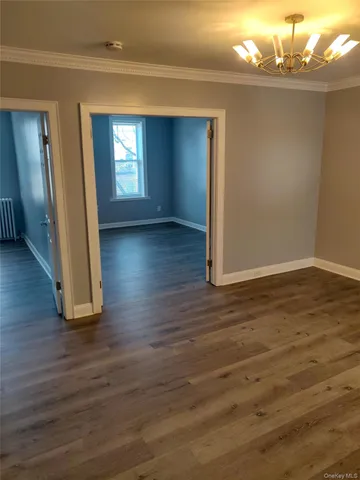 a view of empty room with window and wooden floor