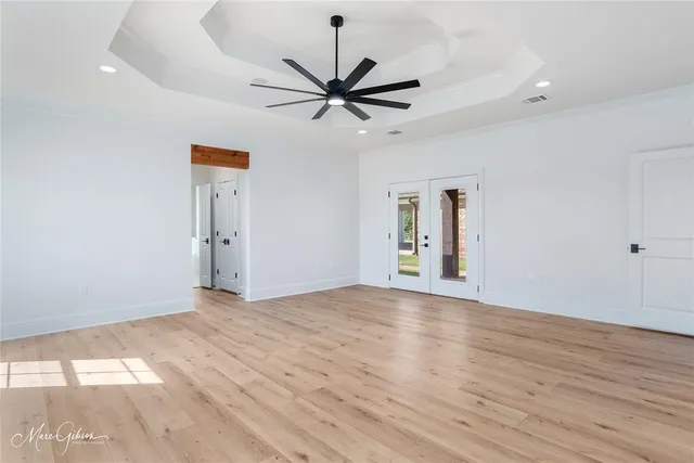 a view of empty room with wooden floor and fan
