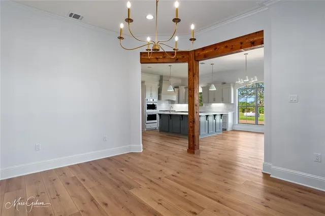 an empty room with wooden floor and kitchen view
