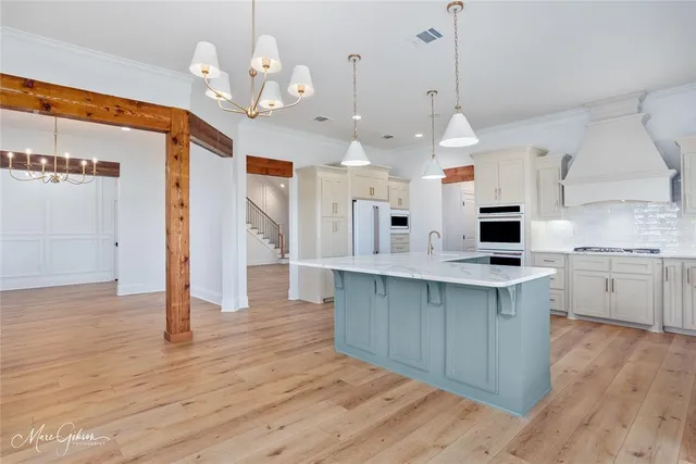 a large kitchen with stainless steel appliances kitchen island granite countertop a sink cabinets and wooden floor