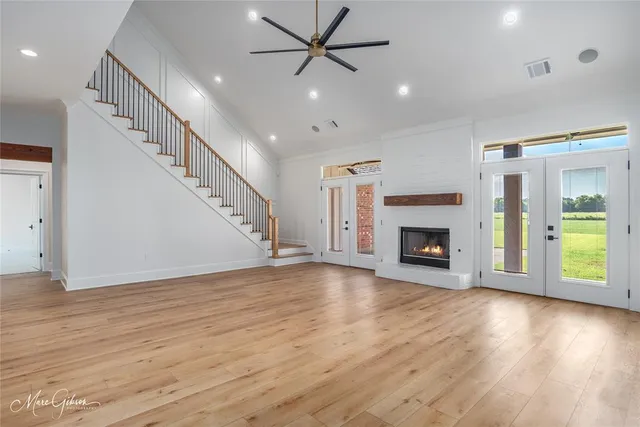 a view of an empty room with wooden floor fireplace and a window
