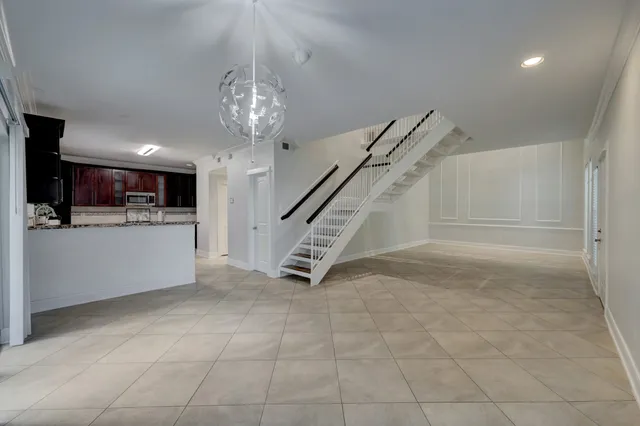 a view of a livingroom with stairs kitchen view and a chandelier
