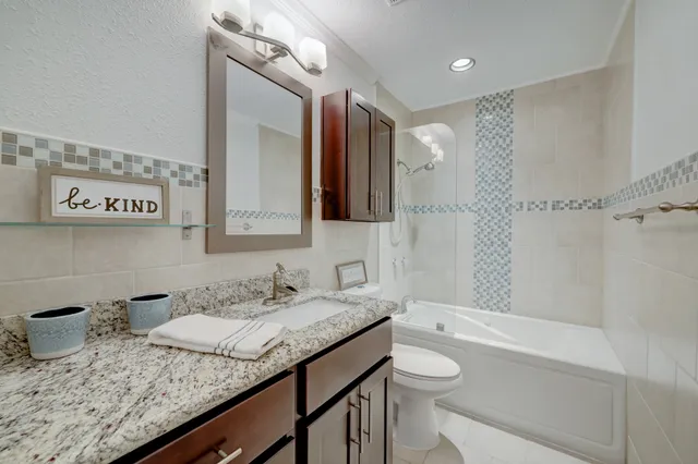 a bathroom with a granite countertop sink a toilet and shower