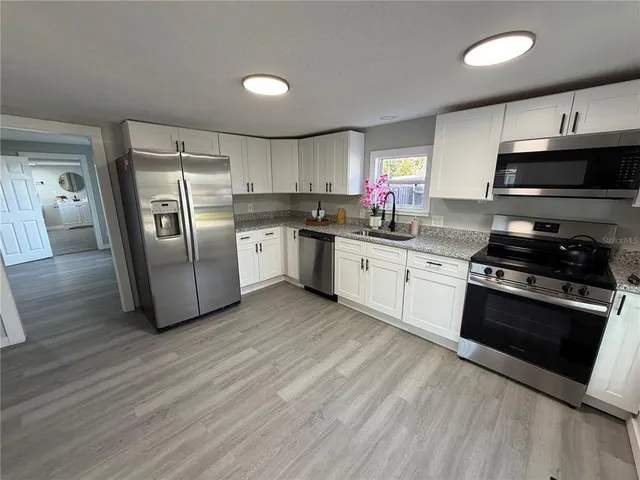 a kitchen with stainless steel appliances granite countertop a stove a sink and a refrigerator
