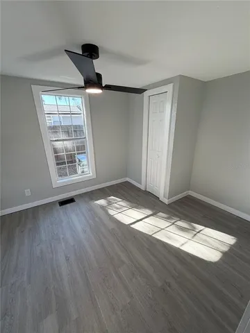 a view of empty room with wooden floor and fan