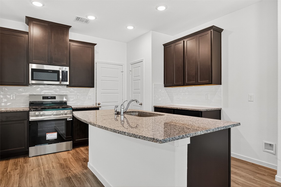 20835 Attalos Stoa Road Crosby, TX 77532 - Photo 16 of 46 a kitchen with kitchen island granite countertop stainless steel appliances stove microwave refrigerator and sink
