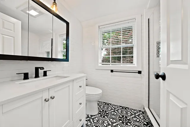a bathroom with a sink a toilet a window and vanity