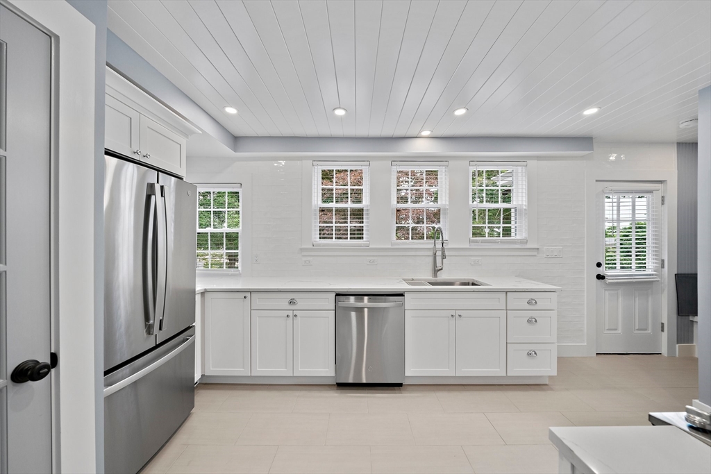 37 Wolcott Road, Unit 37 Brookline, MA 02467 - Photo 9 of 40 a large white kitchen with granite countertop a refrigerator and white cabinets
