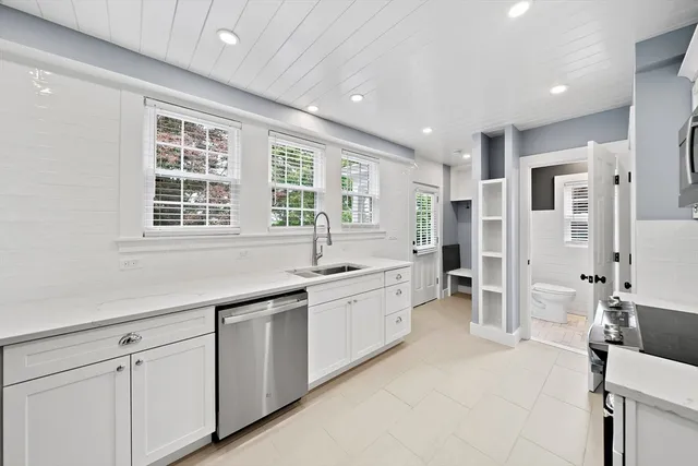 a large white kitchen with granite countertop a sink and dishwasher with a large window