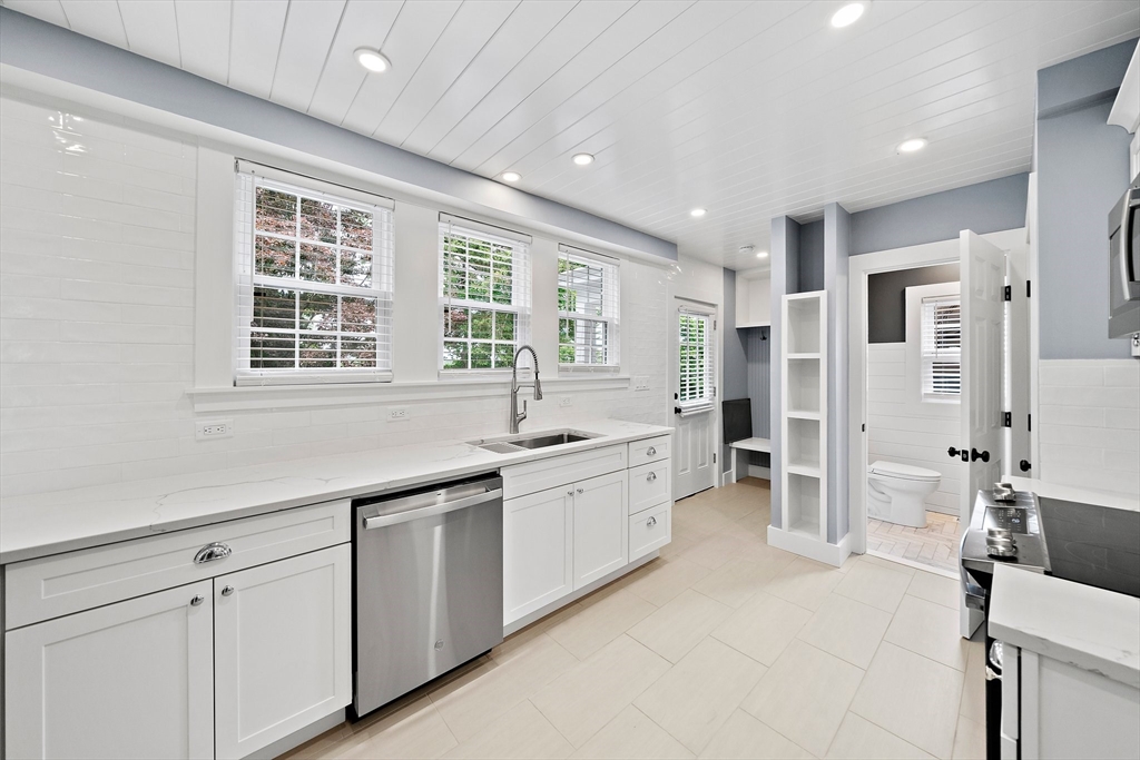 37 Wolcott Road, Unit 37 Brookline, MA 02467 - Photo 10 of 40 a large white kitchen with granite countertop a sink and dishwasher with a large window