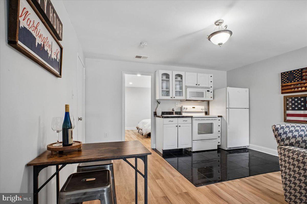 11514 Sunder Court Reston, VA 20190 - Photo 39 of 81 a kitchen with granite countertop a refrigerator a stove a sink and white cabinets with wooden floor