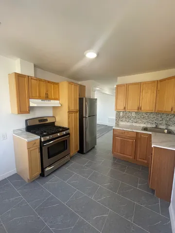 a kitchen with granite countertop a refrigerator and a stove top oven