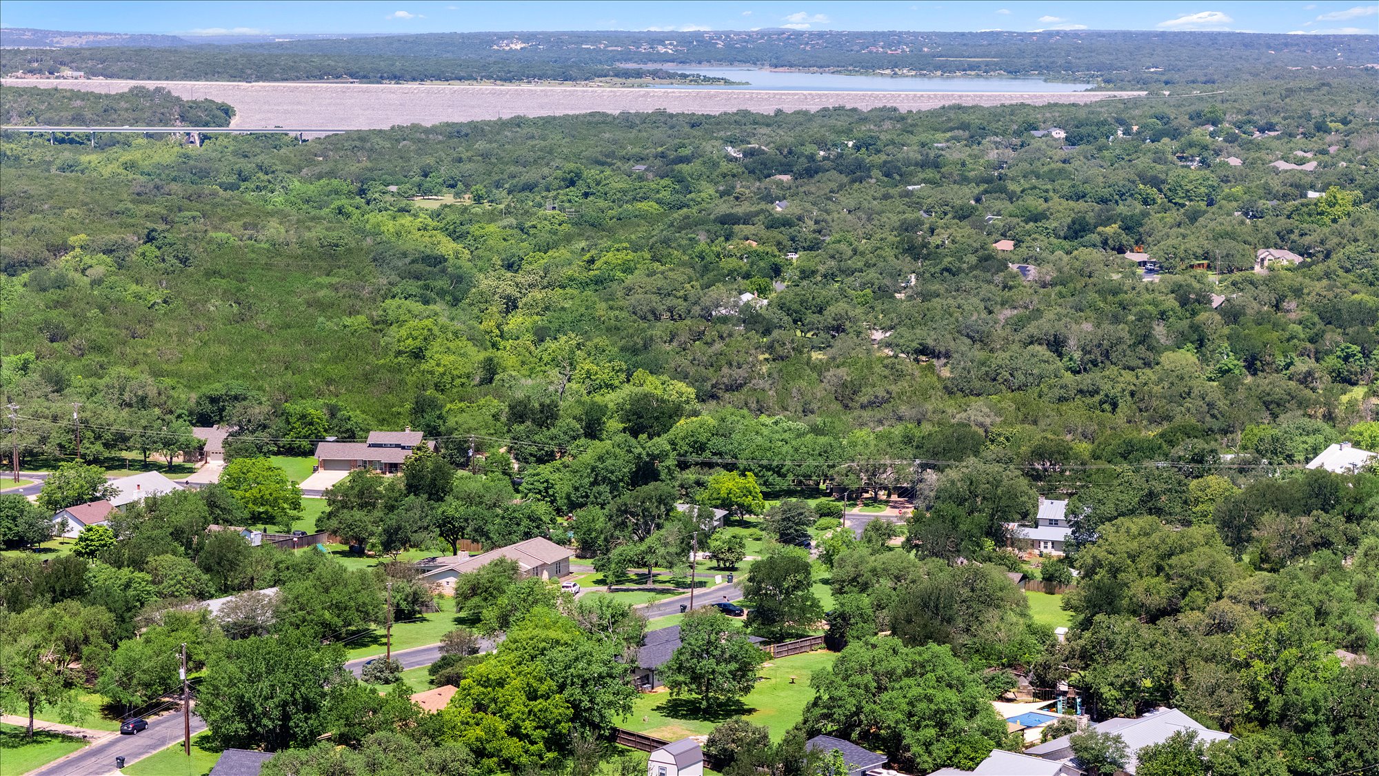 109 Woodland Road Georgetown, TX 78628 - Photo 8 of 40 An aerial panorama reveals a residential enclave nestled amongst verdant trees, with a distant reservoir.