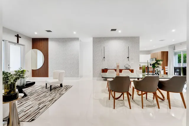 a living room with furniture a potted plant and open kitchen view